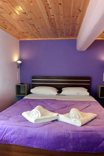 ein lila Schlafzimmer mit einem Bett mit zwei Handtüchern darauf in der Unterkunft Tokastro2 in Arachova