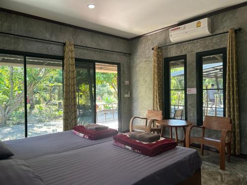 - une chambre avec 2 lits, une table et des fenêtres dans l'établissement บ้านสราญรัตน์, à Ban On Luai