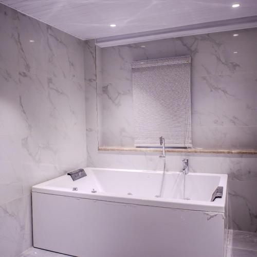 eine weiße Badewanne in einem Badezimmer mit Fenster in der Unterkunft Pinnacle Residences, Kathmandu in Kathmandu