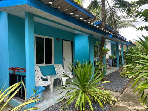 a blue house with white chairs and a table at Lanta bluewave Bungkalow in Ko Lanta