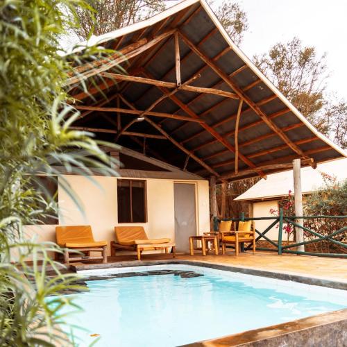 un padiglione sopra una piscina con tavolo e sedie di Manyatta Camp a Voi