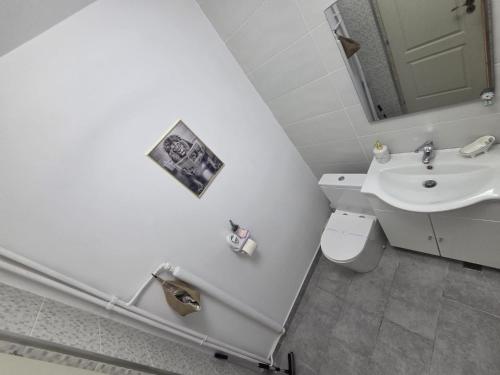 a white bathroom with a sink and a toilet at NGR Residence in Ploieşti