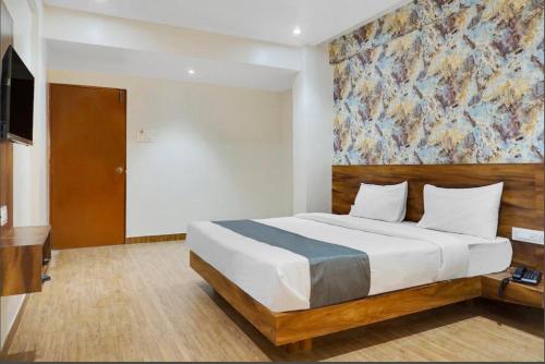 a bedroom with a bed with a large painting on the wall at Omkar Executive in Pune