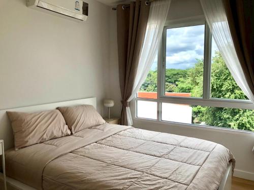 a bedroom with a bed and a large window at Kalpapruek Grand Park near Central Plaza Pool&Gym in Ban San Ton Ko (1)
