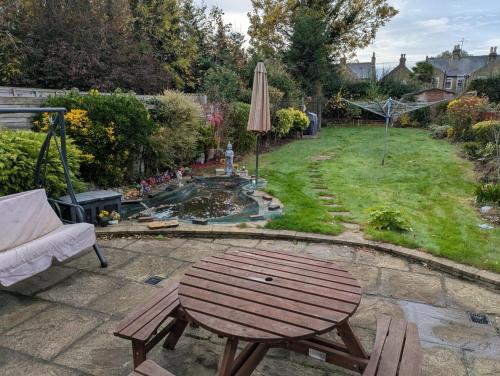 a patio with a table and an umbrella and a pond at Large Central Lodge Near Heathrow Airport & London with Parking in Langley Station