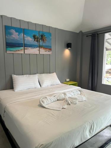 a bedroom with a white bed with palm trees on it at Hangover Chill & Hill Hostel in Phi Phi Islands