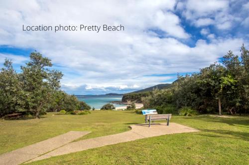 un banc assis sur l'herbe près de l'océan dans l'établissement Retro Beach Cottage - classic surf getaway, à Kioloa