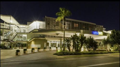 un grand bâtiment avec un palmier devant dans l'établissement Bugluma - Cotton Beach, à Casuarina