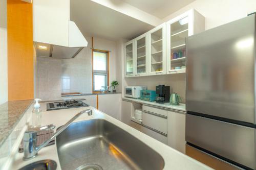 a kitchen with a sink and a stainless steel refrigerator at 読谷Nagahama270度4LDK オーシャンビュー最上階民宿 in Yomitan
