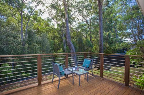Un patio con dos sillas y una mesa en una terraza. en Leafy Retreat - spacious holiday home near harbour, en Ulladulla