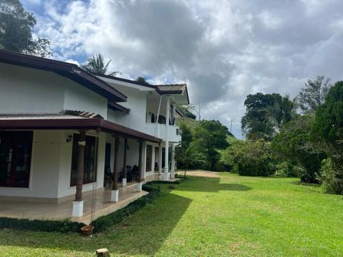 a house with a grass yard in front of it at Upton Estate Homestay in Deniyaya