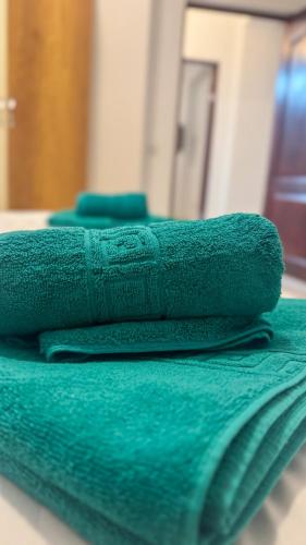 three green towels sitting on top of a bed at Sweet Inn Apartment in Piteşti
