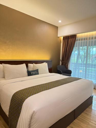 a hotel room with a large bed and a chair at Hotel Insitu Garut Syariah in Garut