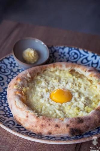 a pizza with an egg on a plate on a table at Billionare In Alliance Palace in Batumi
