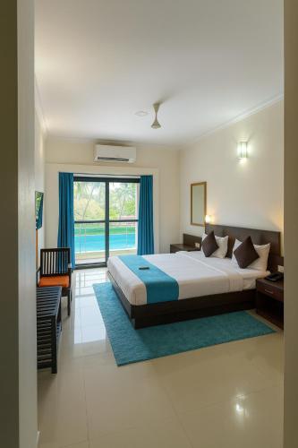 ein Schlafzimmer mit einem Bett und einem großen Fenster in der Unterkunft Hotel Shiva Classic, Calangute Beach Goa in Calangute