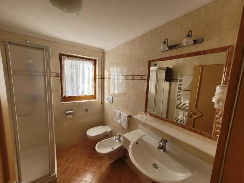 een badkamer met een wastafel, een toilet en een spiegel bij Chalet Milandora in La Villa