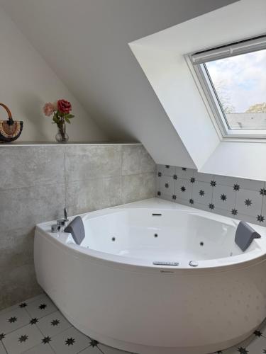 une baignoire blanche dans une salle de bains avec fenêtre dans l'établissement Ty Cocon - havre de paix avec jacuzzi, à Rochefort-en-Terre