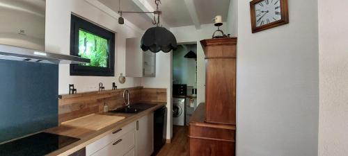 een keuken met een wastafel en een klok aan de muur bij L'Escandihado in Saint-Étienne-du-Grès