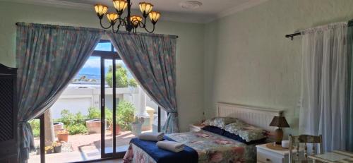 Un dormitorio con una cama y una ventana grande. en Arendsnest, en Gordonʼs Bay