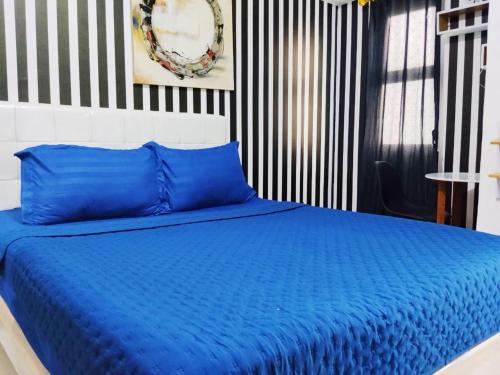 a bedroom with a blue bed with a black and white wall at Antareja Urban Town By Reccoma in Dukuh