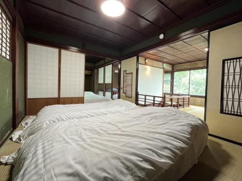 uma grande cama branca num quarto com janelas em 古民家宿 禅楽 em Shimminato
