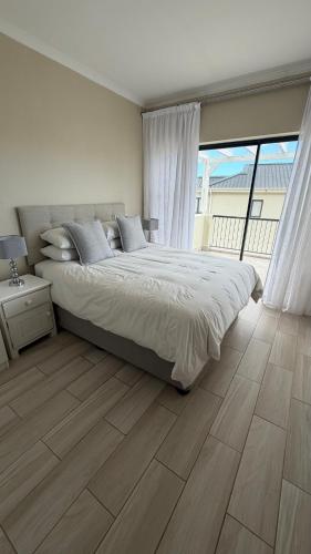 a bedroom with a large bed and a large window at Villa on Private Estate with Pool in Hermanus
