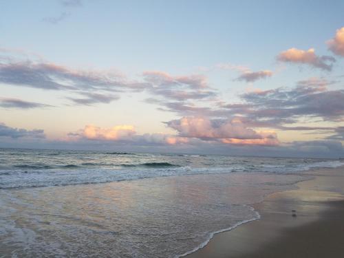 a beach with a cloudy sky and the ocean at First Colony Inn in Nags Head
