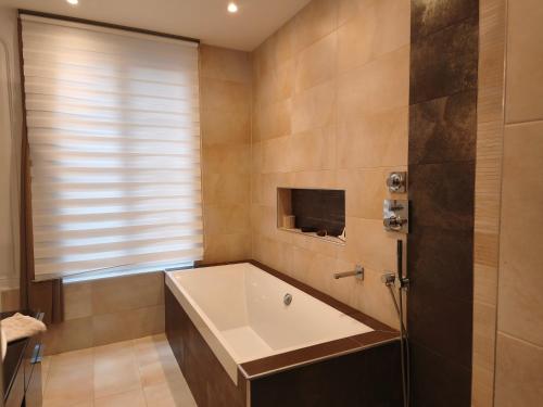 a bathroom with a large tub and a window at Le Vieux Palais Hypercentre Rouen, Place Vieux Marché - Linge & Ménage Inclus in Rouen