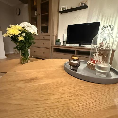 Una mesa con un jarrón de flores y un televisor. en Ferienwohnung SüntelLoft, en Hameln