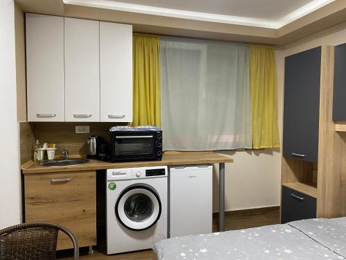 une cuisine avec un lave-linge et un micro-ondes dans l'établissement Apartmani N&D, à Kumanovo