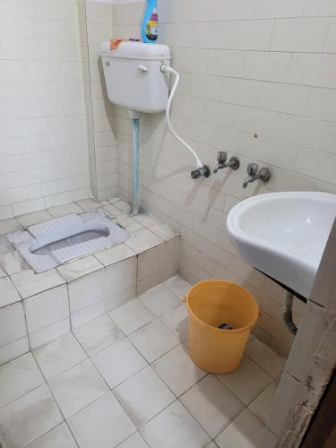 a bathroom with a toilet and a sink and a bucket at The Family Nest in Hyderabad