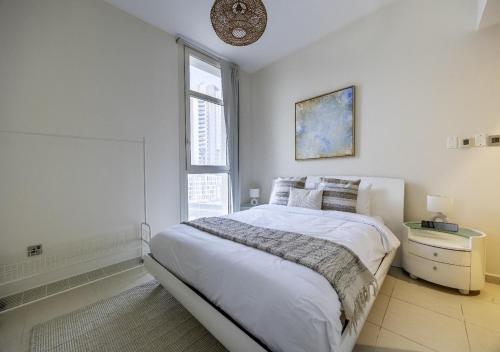 a white bedroom with a bed and a window at Iconic HF BR Hall 2 Bath Balcony Free- Parking, Pool, Gym & 2 Kids - Al Reem Island in Abu Dhabi