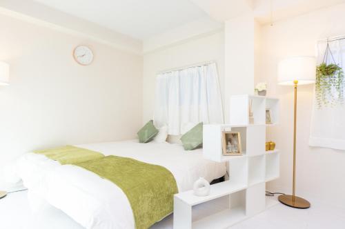 a white bedroom with a bed and a lamp at Miraie Katano Stay in Kisabe