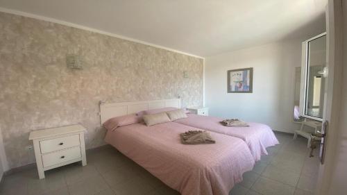 una camera da letto con un letto con lenzuola rosa e un tavolo di Apt. El Guirre Nº 3 a Valle Gran Rey