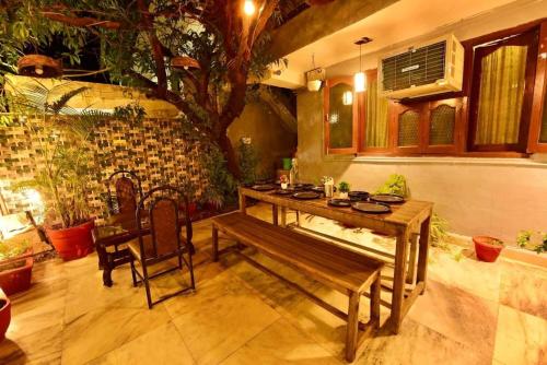 Una mesa y un banco de madera en una habitación con un árbol. en The Boho Peach Villa, en Mount Abu