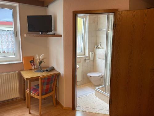 a bathroom with a toilet and a table and a television at Appartement an der Steinach in Nagold