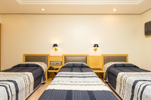 three beds in a row in a room at Hotel Columbia in Sao Paulo