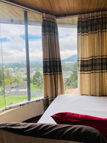 a bed in a room with a large window at Niwasa Hills in Nuwara Eliya