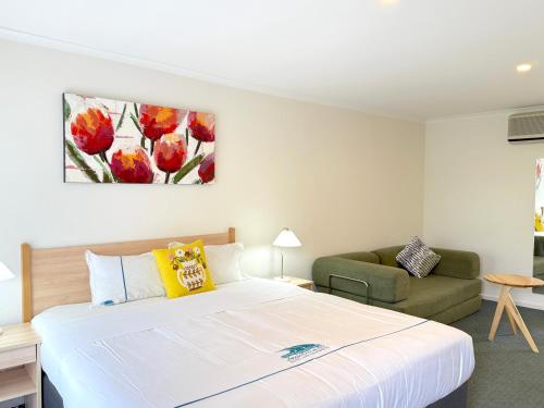 a bedroom with a large bed and a couch at Beachcomber Motel & Apartments in Apollo Bay