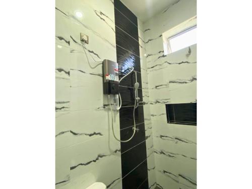La salle de bains est pourvue d'une douche avec du carrelage noir et blanc. dans l'établissement Hijrah De La Villa Parit Buntar Nibong Tebal Penang, à Nibung Tebal