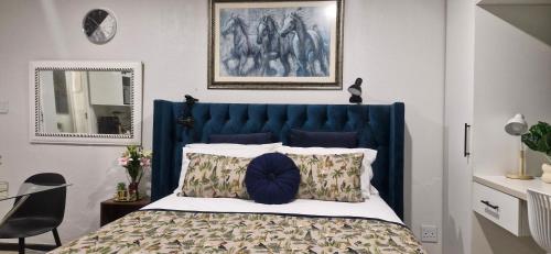 a bed with a blue headboard in a bedroom at The Little Haven in Midrand