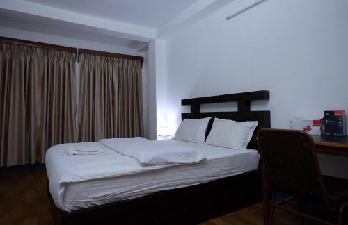 ThapathaliMakalu Apartment 2BHK Thamel 5 min walk 1st Floor的一间卧室配有一张带白色床单的床和一张书桌。