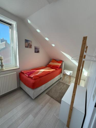 Schlafzimmer mit einem Bett mit roter Bettwäsche und einer Leiter in der Unterkunft Wohnen beim Klabautermann mit Südbalkon in Wilhelmshaven