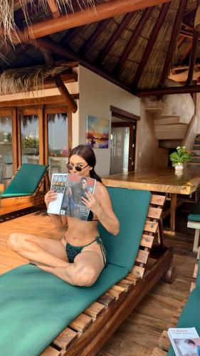 a woman sitting on a couch reading a book at Casa Playa Verde - 200Mbps Wifi in Troncones