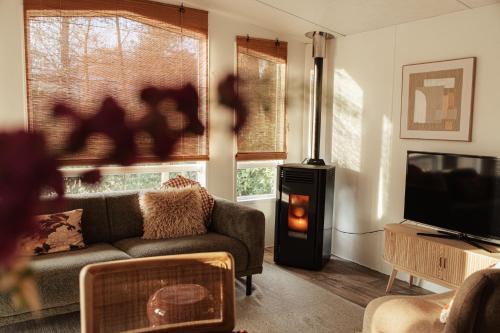 a living room with a couch and a wood stove at Boshuisje met kachel "Huisje van Loof" op de Veluwe in Nunspeet
