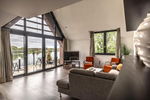 a living room with a couch and a large window at Het Maashotel in Broekhuizen