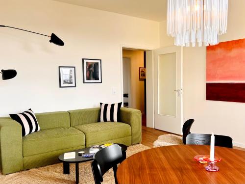 a living room with a green couch and a table at Atelier Noé NOIR - Kunstvoll Wohnen - Wunderbares Frühstück möglich - Ruhig und nah am Zentrum - in Chemnitz