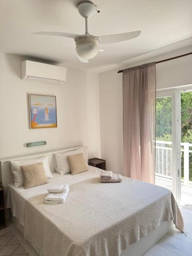 a white bedroom with a large bed and a window at Rose rooms on the island of Rab in Rab