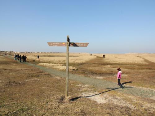 une petite fille debout à côté d'un panneau de rue dans l'établissement Great holiday home energy neutral on Texel with sauna and sun shower, à Westermient