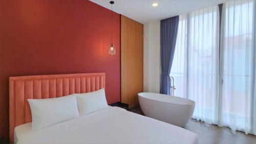 una camera da letto con un letto bianco e una vasca accanto a una finestra di Lovera Hotel Airport ad Ho Chi Minh